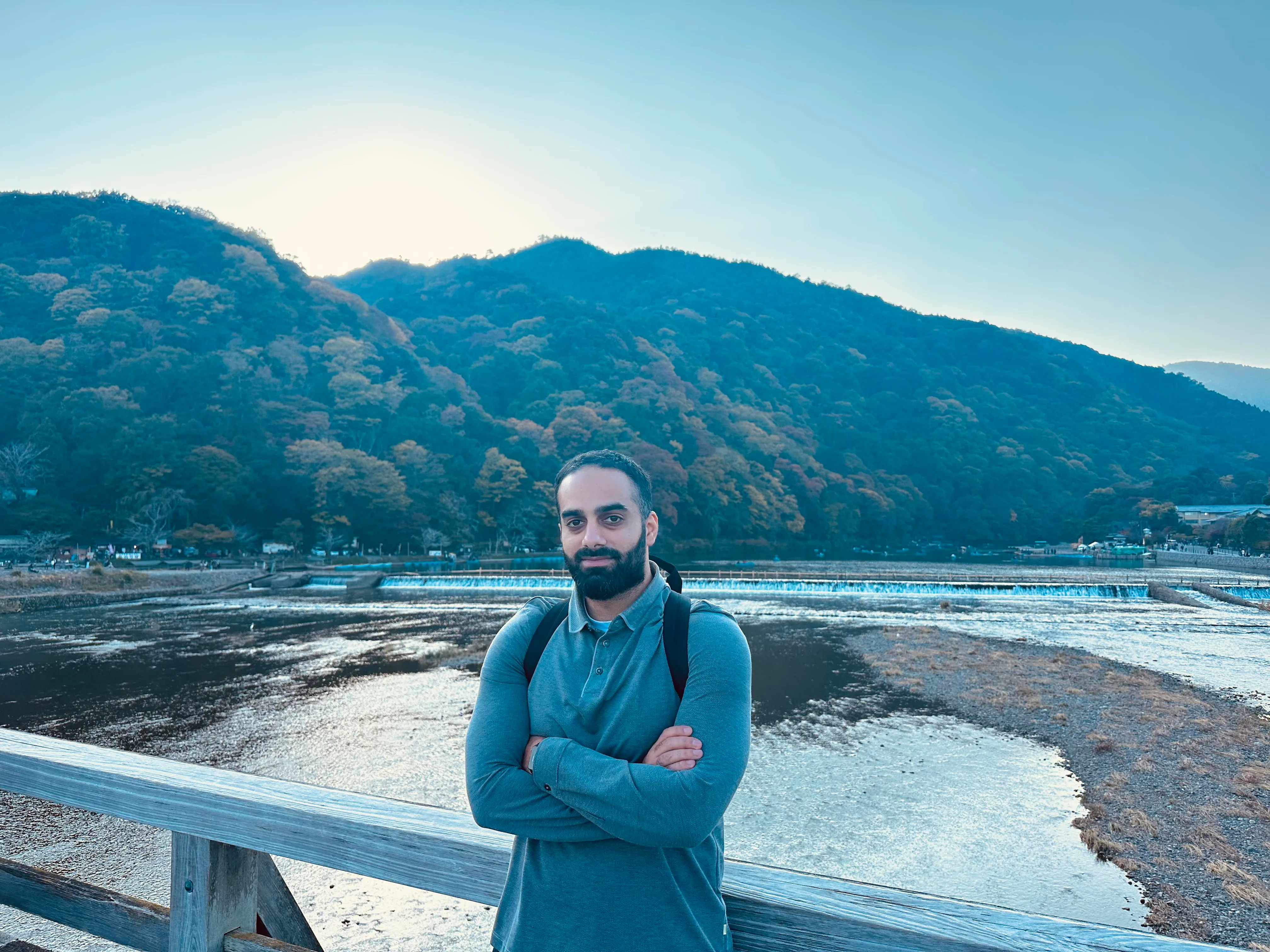 Portrait of Mohammad Afsari beside a river and wooded hills